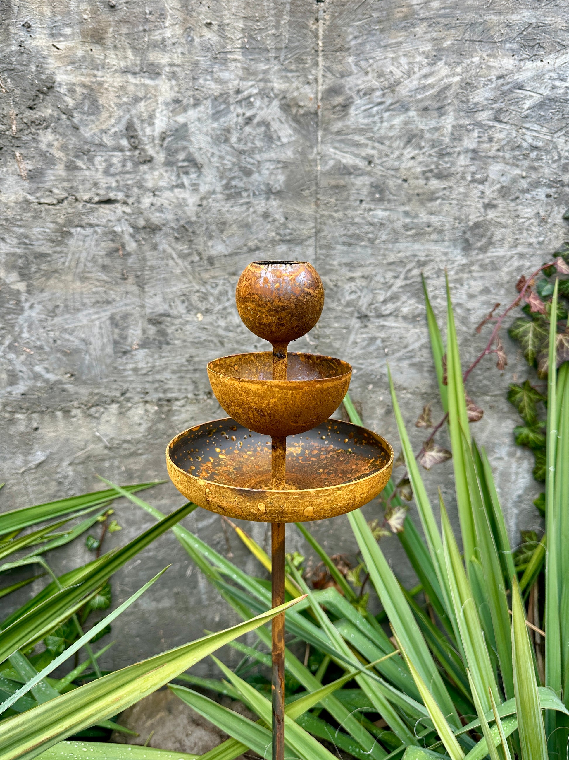 Rusty metal rain catchers, bird baths, bird feeder.