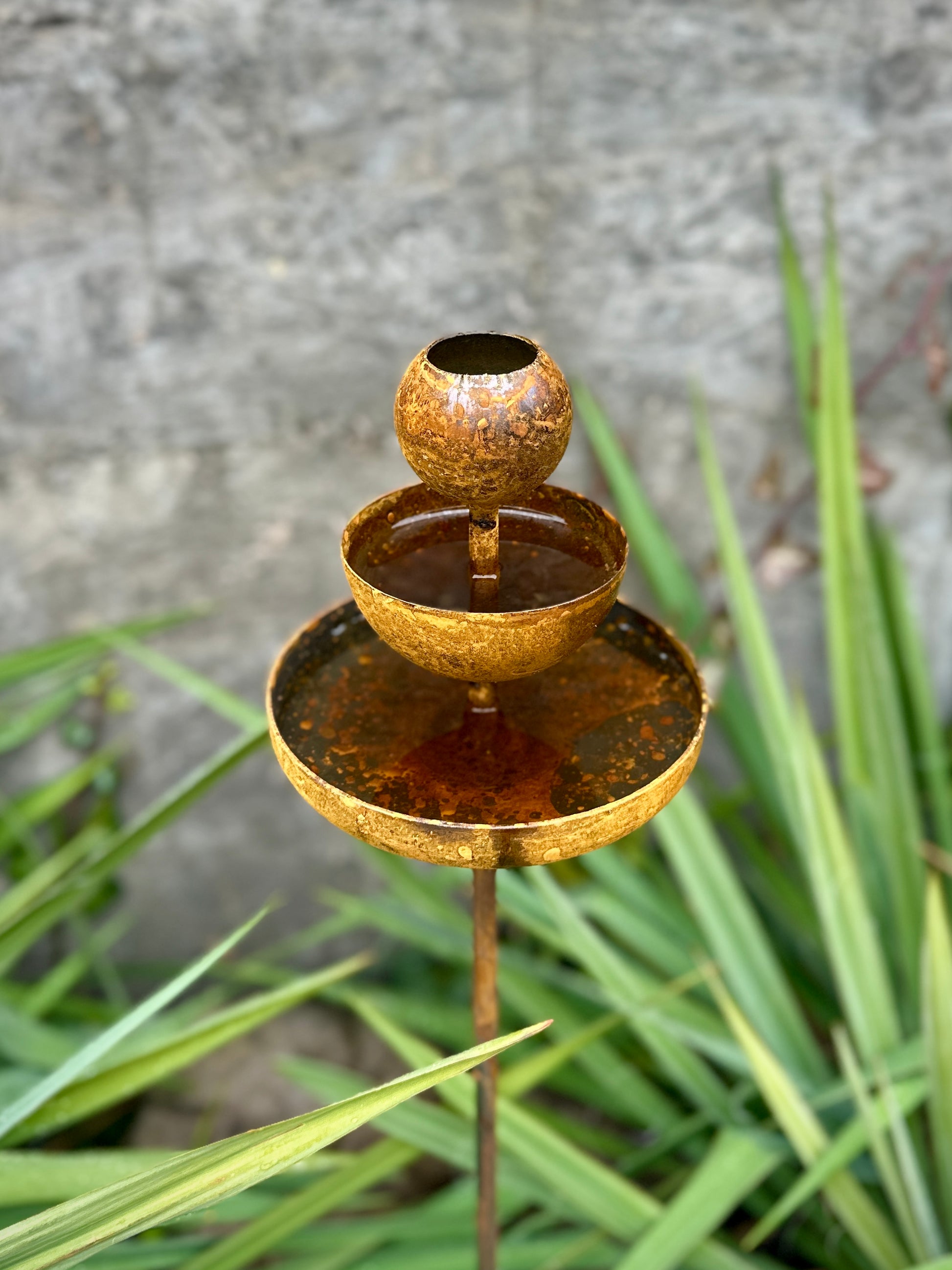 Rusty metal rain catchers, bird baths, bird feeder.