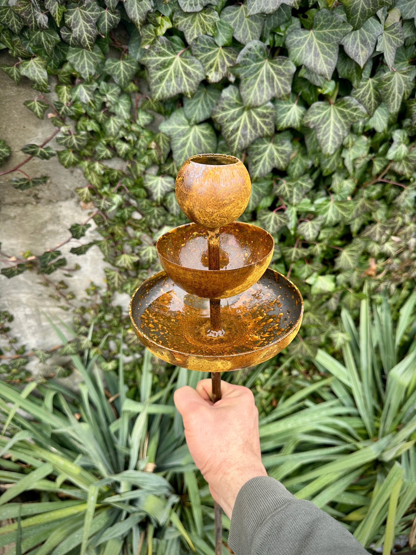 Rusty metal rain catchers, bird baths, bird feeder.