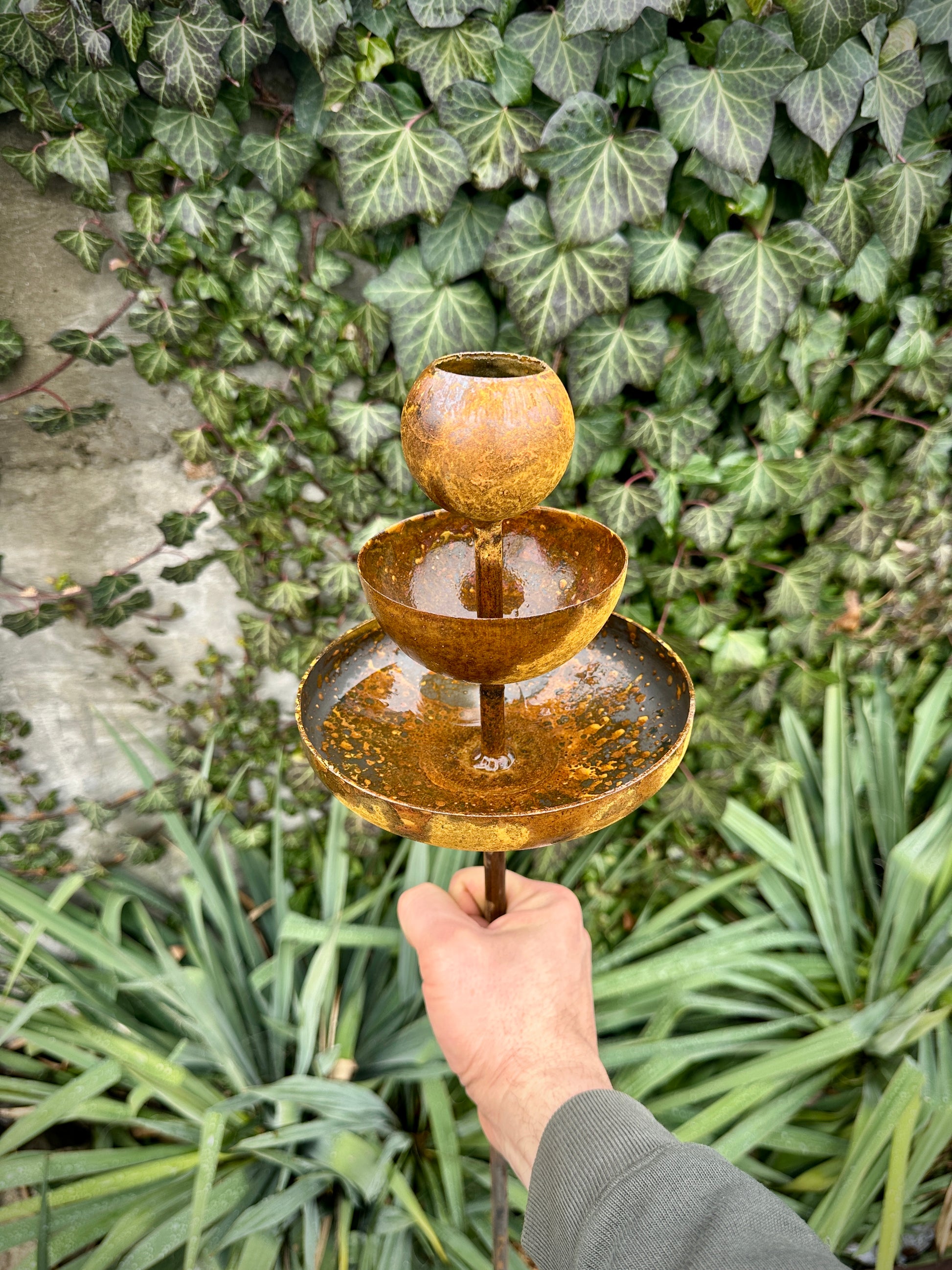 Rusty metal rain catchers, bird baths, bird feeder.