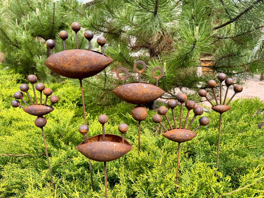 Rust-colored metal garden art pieces on a green bush