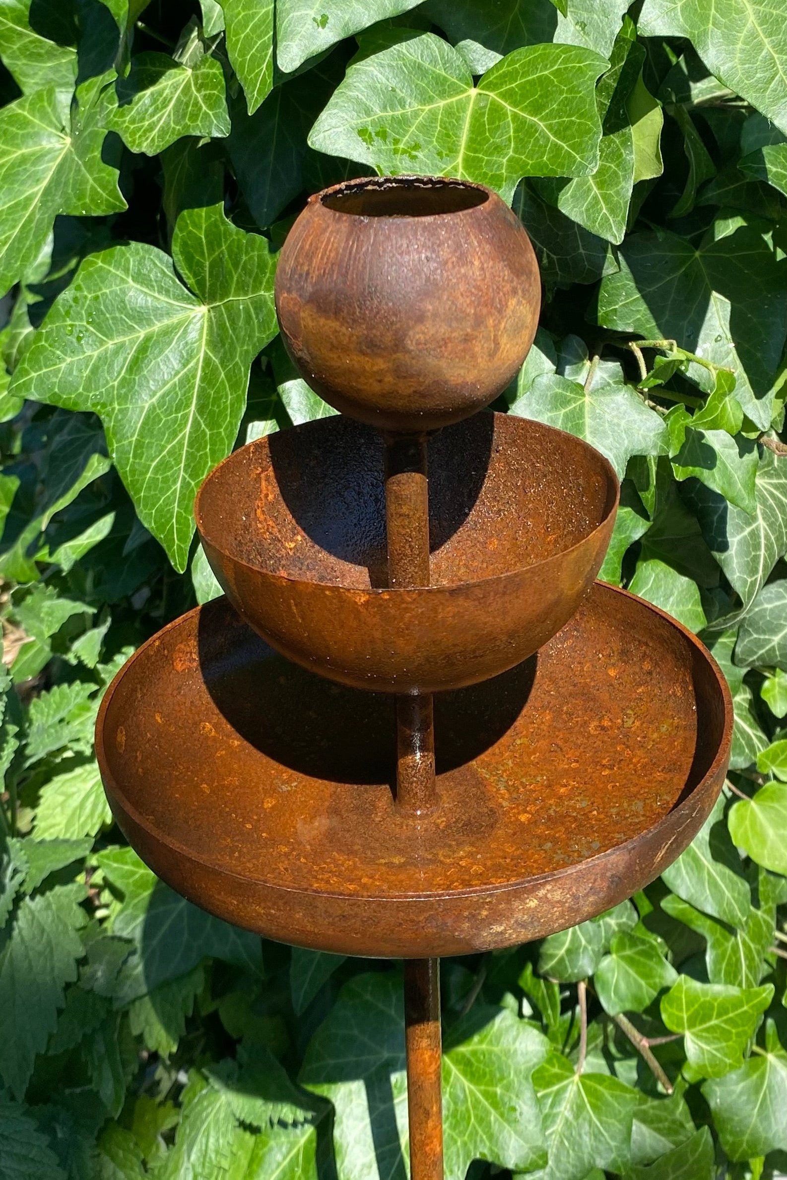 Rusty metal rain catchers, bird baths, bird feeder.