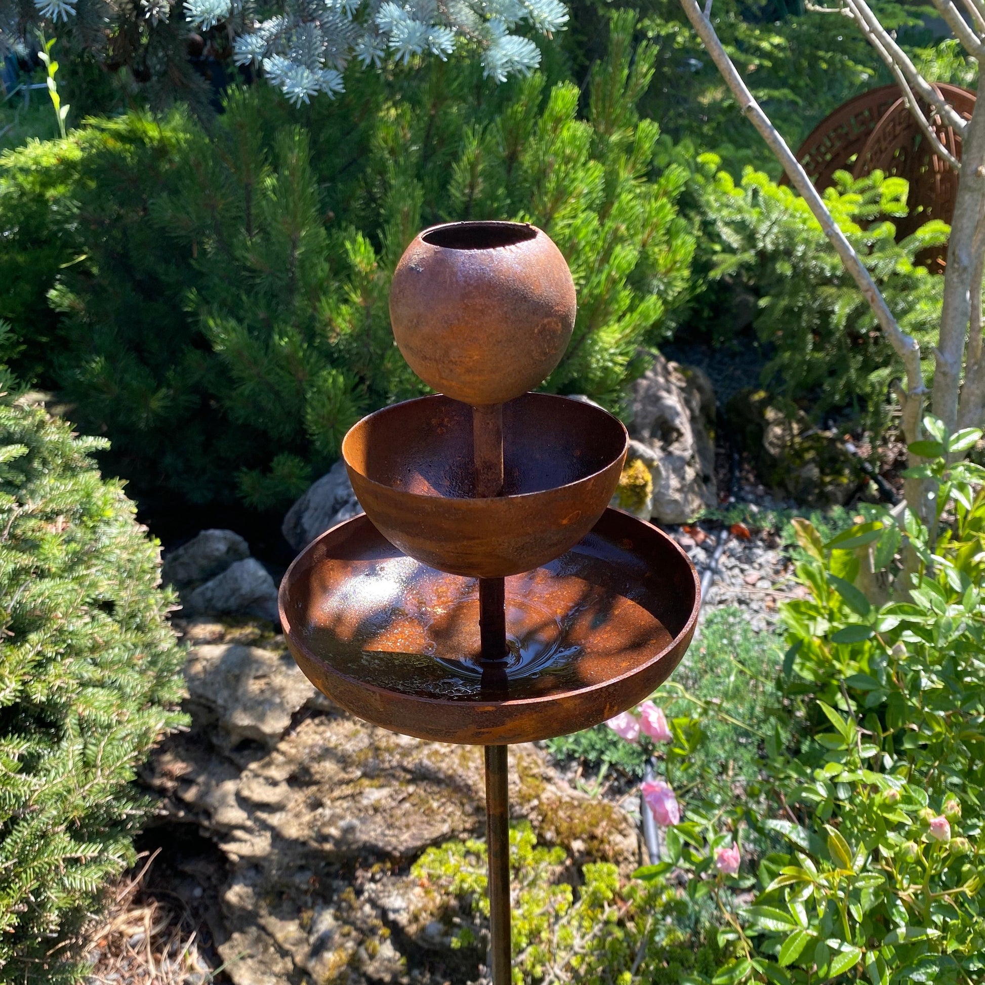 Rusty metal rain catchers, bird baths, bird feeder.