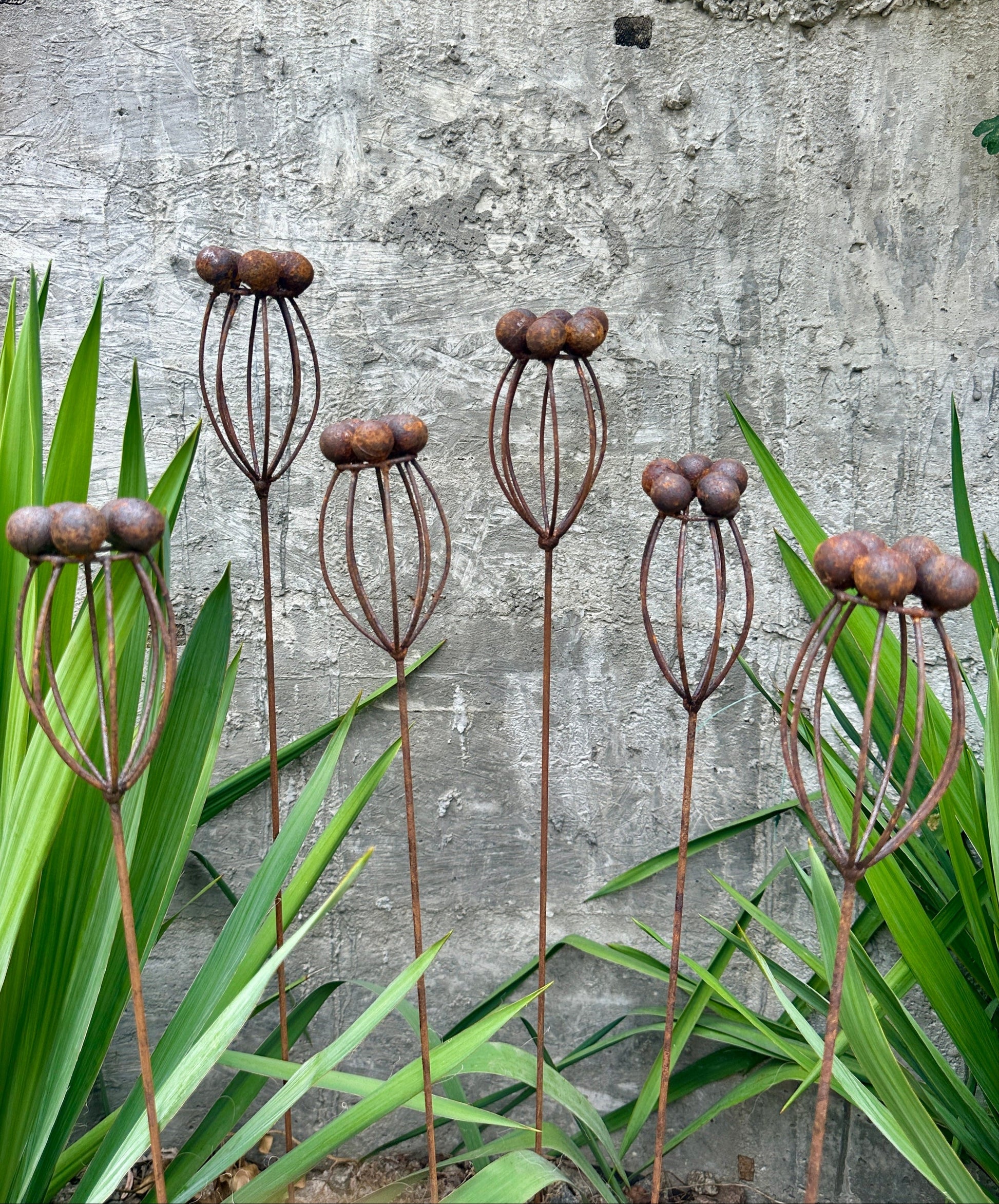 Decorative metal plant stands with a textured wall and green plants in the background