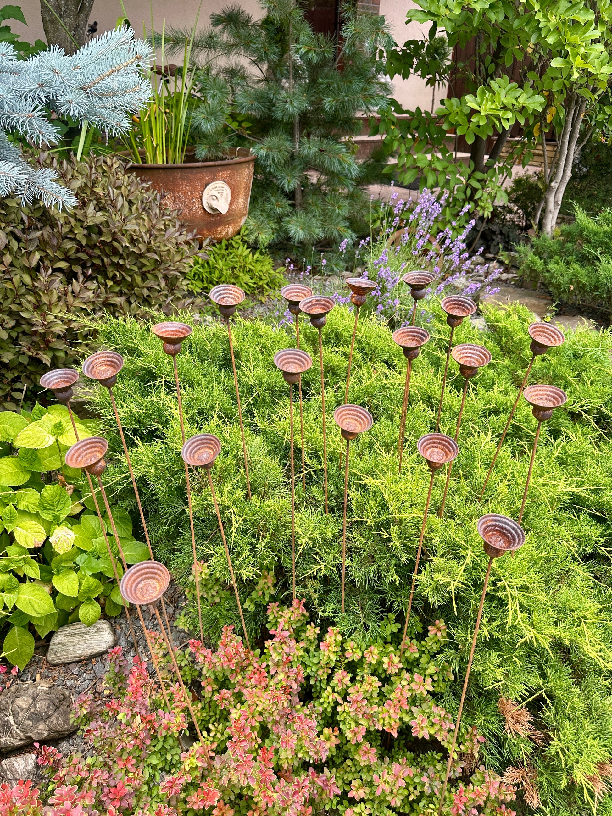 Decorative metal stakes with circular top designs in a garden setting.