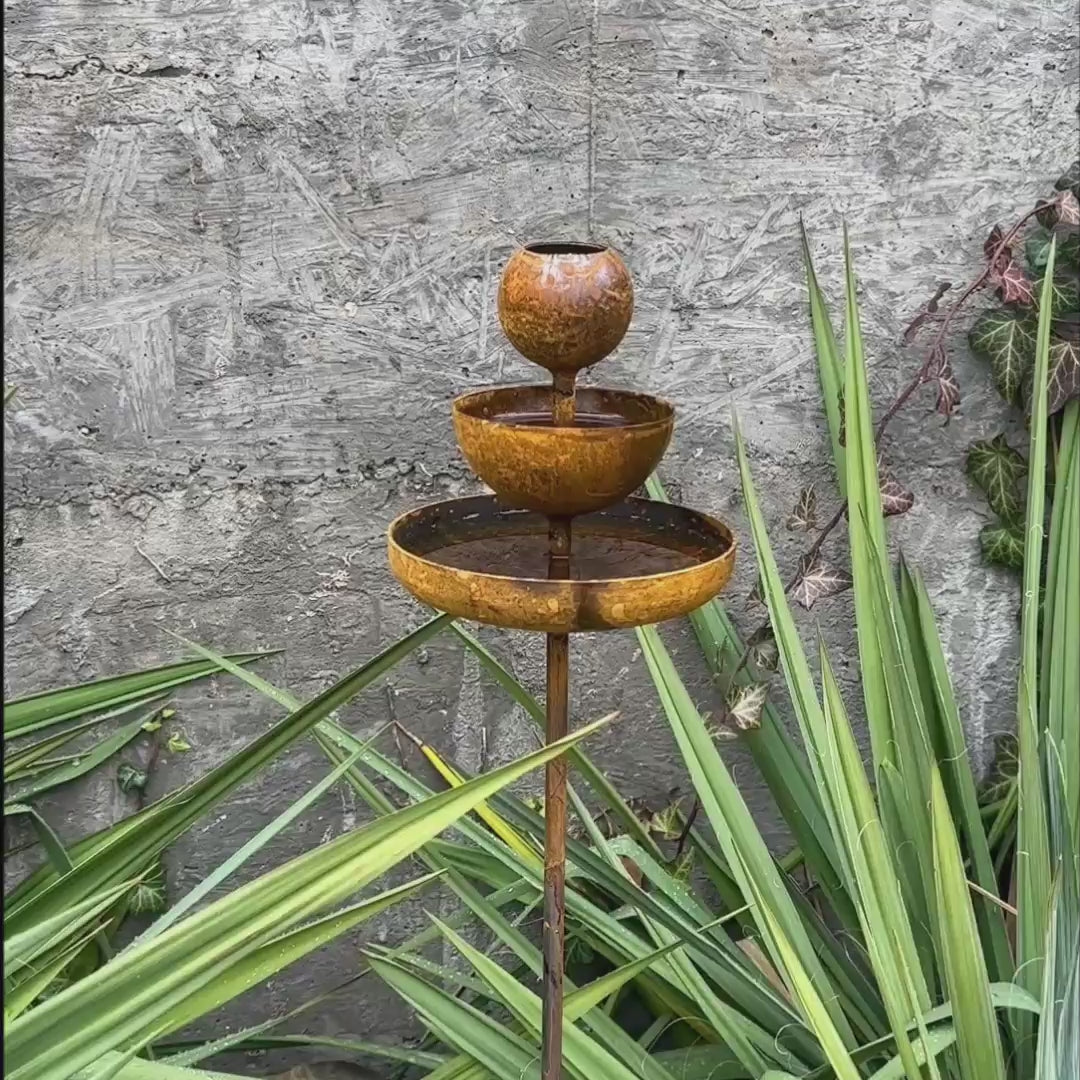 Rusty metal rain catchers, bird baths, bird feeder.