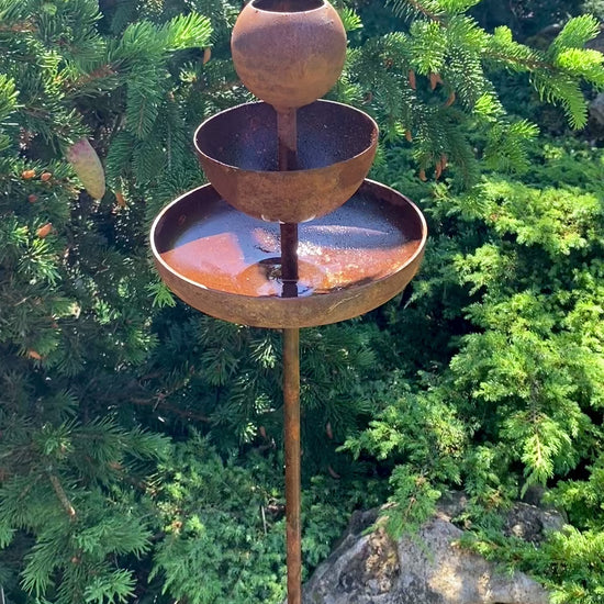 Rusty metal rain catchers, bird baths, bird feeder.