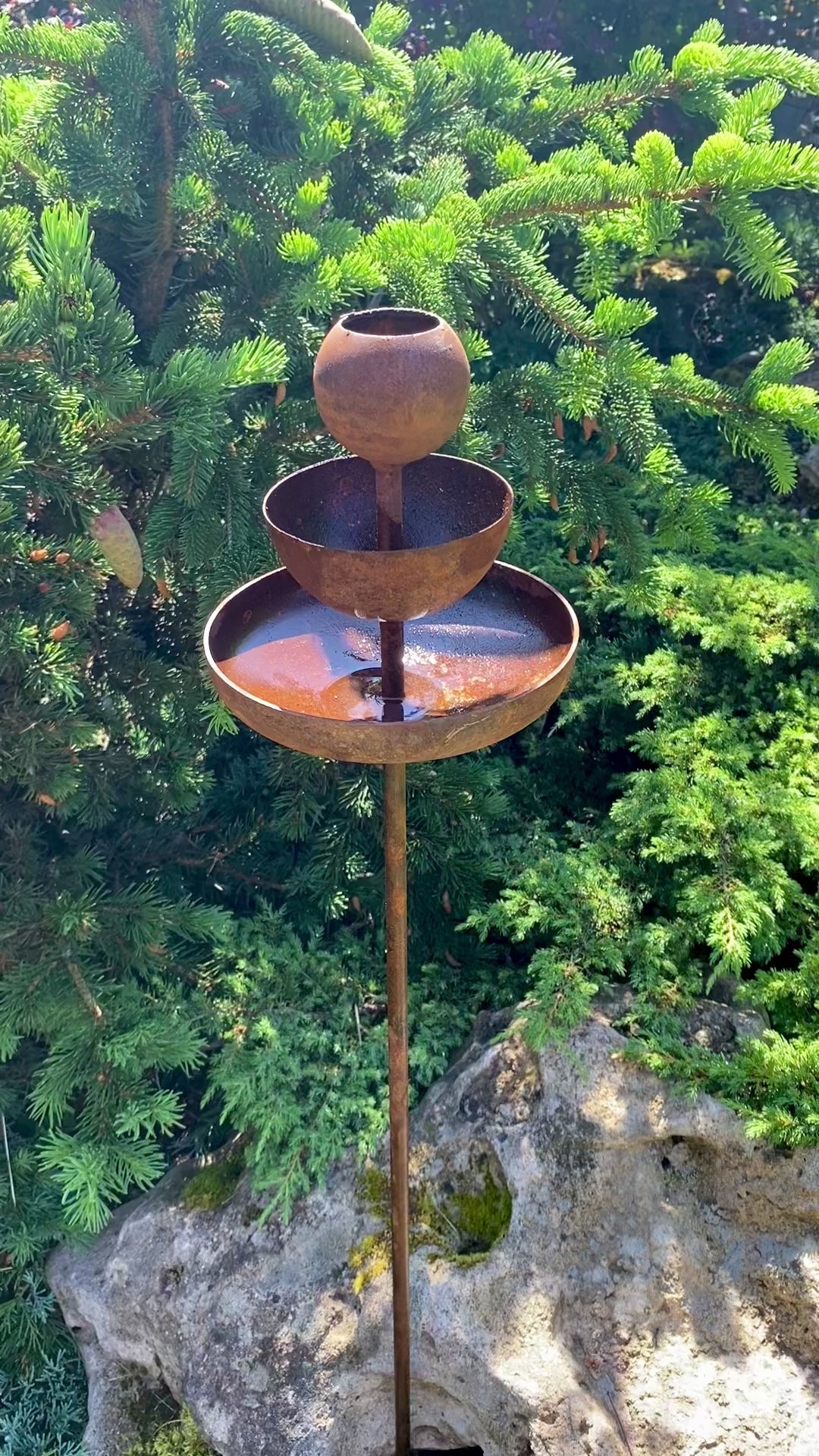 Rusty metal rain catchers, bird baths, bird feeder.